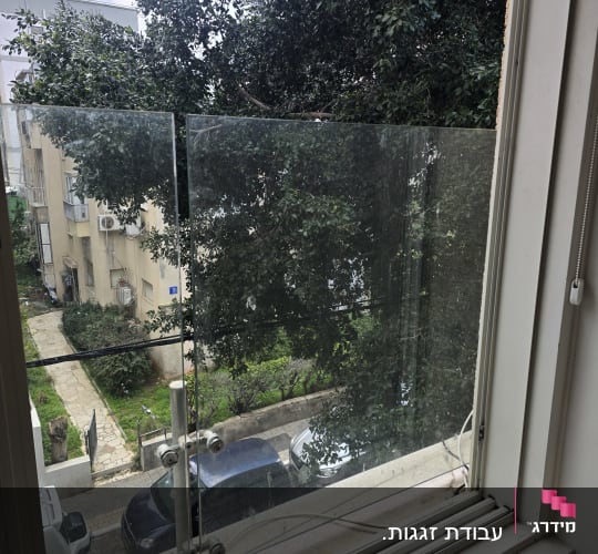 מעקה זכוכית עם נוף לעצים ומכוניות